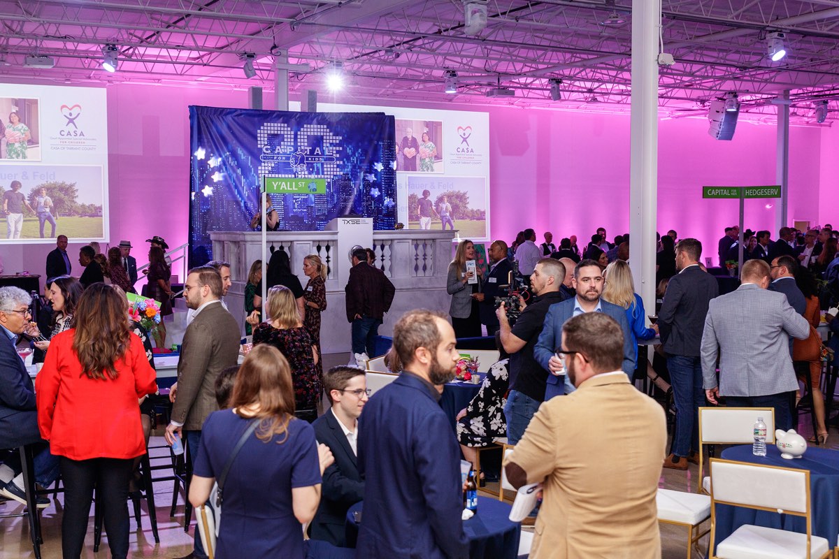 Corporate event with stage, branded screens, and standing crowd lit in color at Astoria Event Venue